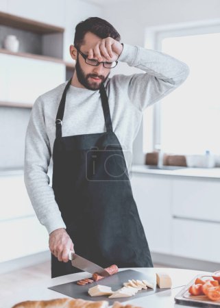 Téléchargez les photos : "fatigué homme fait des sandwichs dans sa cuisine" - en image libre de droit