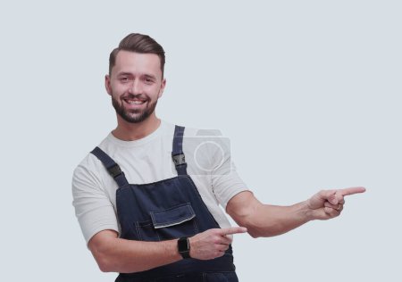 Photo for "smiling man in overalls pointing to a copy of the space" - Royalty Free Image