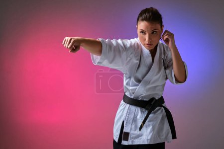 Photo for "Athletic woman in traditional kimono is practicing karate in studio." - Royalty Free Image