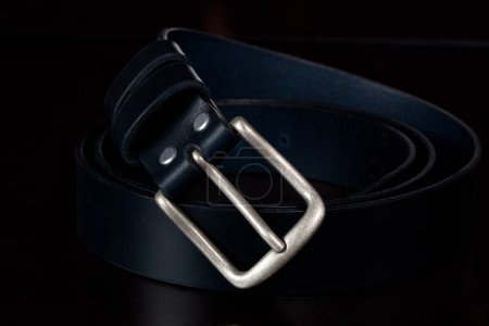 Foto de "Cinturón de cuero con hebilla de metal sobre fondo oscuro." - Imagen libre de derechos