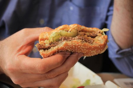 Foto de "Hombre sosteniendo una hamburguesa fresca" - Imagen libre de derechos