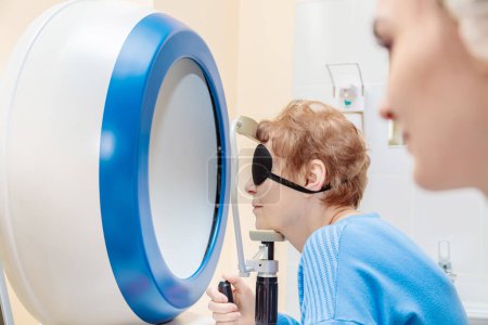Foto de A girl optometrist examines the eyes of a patient using special modern equipment - Imagen libre de derechos