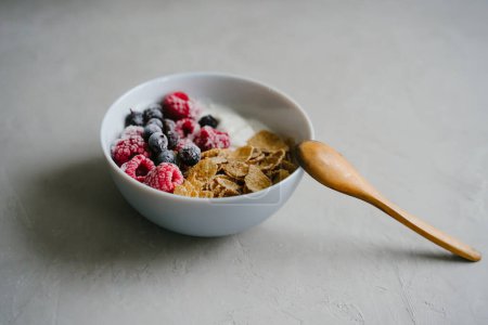 Foto de "Delicioso y saludable desayuno. Yogur natural, cereales y bayas. Cuchara de madera." - Imagen libre de derechos