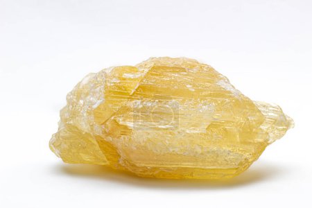 Raw uncut real honey yellow calcite crystal, calcium carbonate mineral with visible structure macro isolated on a white background surface 