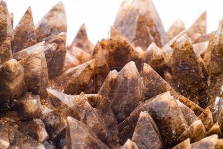 Foto de Macro focused raw natural brown sharp spiked calcite, calcite stone, natural sharp and brown carbonate crystal geode isolated on a white surface background - Imagen libre de derechos