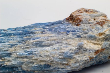 Foto de Macro enfocado crudo sin cortar vibrante azul cianita, hoja mineral de cristal de cianita con impurezas de calcita blanca aisladas sobre un fondo de superficie blanca - Imagen libre de derechos