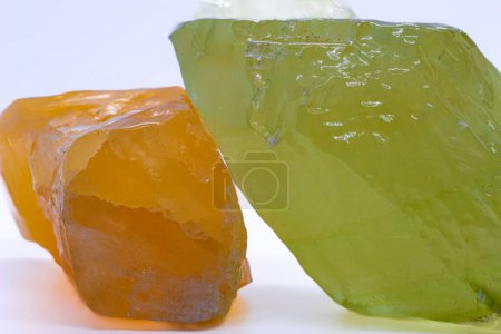 Foto de Macro focused raw shiny semi-transparent vibrant orange and pistachio lime green calcite mineral, calcite stone, two bright carbonate crystals isolated on a white surface background - Imagen libre de derechos