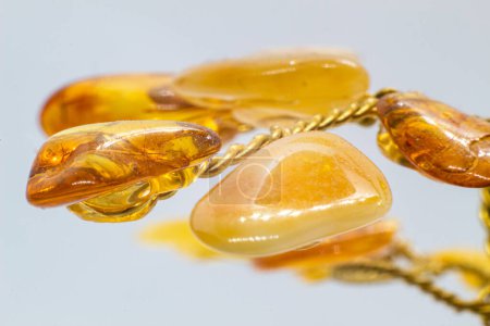 Vibrant yellow and orange polished amber crystal and copper wire tree on a blue chalcedony mineral base macro isolated on white surface