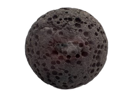 Piedra de lava esférica redonda negra y gris altamente texturizada aislada sobre un fondo de superficie blanca con pequeños agujeros redondos.