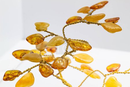 Vibrant yellow and orange polished amber crystal and copper wire tree on a blue chalcedony mineral base macro isolated on white surface