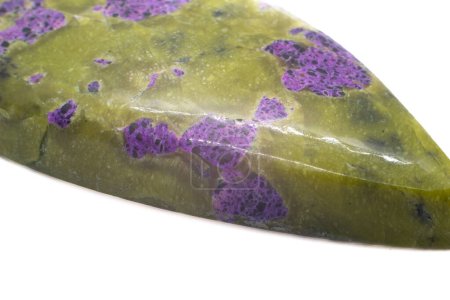 Atlantisit - einzigartiger Stein, der eine Kombination aus einem olivgrünen Serpentinmineral und einem lebendigen violetten Stichtit-Kristall ist, der zu einem Tropfen-Cabochon poliert wurde, isoliert auf einer weißen Oberfläche.
