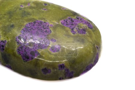 Atlantisit - einzigartiger Stein, der eine Kombination aus einem olivgrünen Serpentinmineral und einem lebendigen violetten Stichtit-Kristall ist, der zu einem Tropfen-Cabochon poliert wurde, isoliert auf einer weißen Oberfläche.