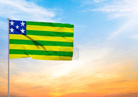 Illustration 3D d'un drapeau Goias étendu sur un mât de drapeau et en arrière-plan un beau ciel avec un coucher de soleil
