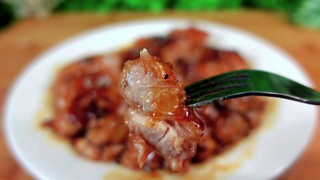 Téléchargez les photos : Delicious chicken meat in sauce on a fork on a background of a plate - en image libre de droit