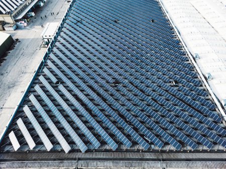 Foto de Vista aérea de paneles solares en edificios industriales. Punto de vista del dron, volando sobre el área industrial, con techos cubiertos de paneles solares. - Imagen libre de derechos
