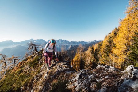 Foto de Vista panorámica de la montaña de otoño, Alpes europeos, desde un punto de vista, donde la mujer senderista caucásica está de pie. El sol brilla en lo alto de las montañas, brilla una ligera niebla en los valles. Mujer. - Imagen libre de derechos