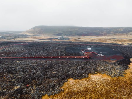 Foto de Central Geotérmica, central eléctrica de agua caliente en Islandia. Vapor saliendo de las chimeneas de la planta, grandes tubos rojos corriendo por los terrenos llenos de agua caliente. Sostenible, energéticamente eficiente - Imagen libre de derechos