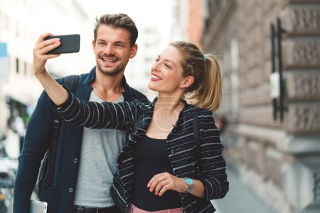 Photo for Young millennial couple living in the city, taking a selfie with a smart phone. - Royalty Free Image