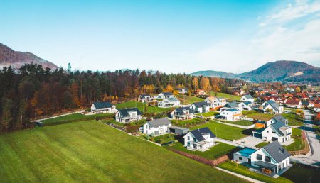 Photo for Aerial view, drone flying over new housing development in the country side. Family homes in the suburbs surrounded with forest and green fields. - Royalty Free Image