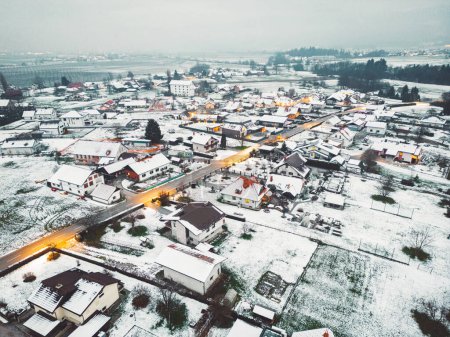 Téléchargez les photos : Aerial view of suburban community in winter time in the evening. Snow on the grounds, dark, street lights shining. - en image libre de droit