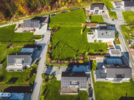 Téléchargez les photos : Vue aérienne, drone survolant un nouveau lotissement à la campagne. Maisons familiales dans la banlieue entourée de forêts et de champs verts. - en image libre de droit