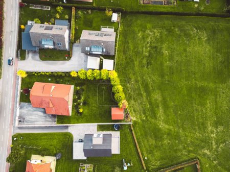 Téléchargez les photos : Vue aérienne, drone survolant la banlieue à la campagne. Maisons familiales dans la banlieue entourée de forêts et de champs verts. - en image libre de droit