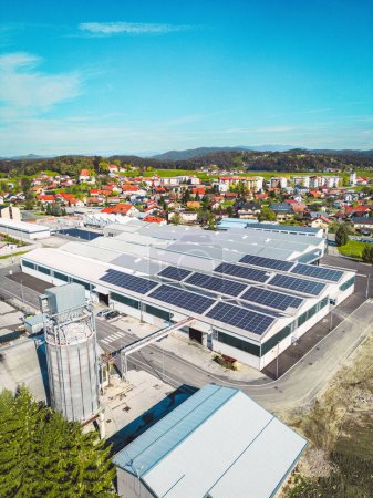 Foto de Aerial view of a factory in the suburbs with roof top covered with solar panels. High quality photo - Imagen libre de derechos