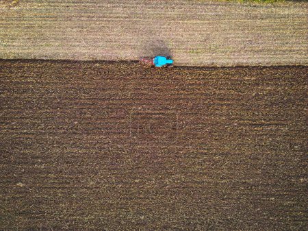 Téléchargez les photos : Aerial view of a tractor ploughing a field, a farmer in a modern tractor ploughing field on a sunny day. High quality photo - en image libre de droit