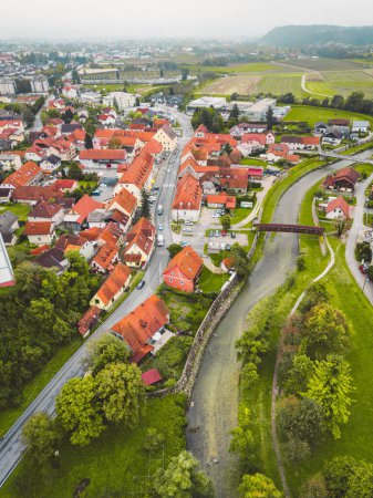 Téléchargez les photos : Drone stills of a small town in the countryside in autumn. River running trough the town, aerial view. - en image libre de droit