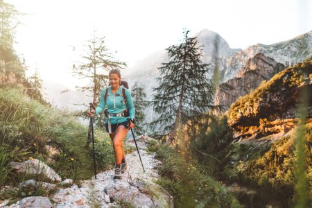 Foto de Caminata de mujer caucásica con mochila en el hermoso sendero en los Alpes europeos temprano en la mañana. Concepto de Viajes y Aventura. Foto de alta calidad - Imagen libre de derechos
