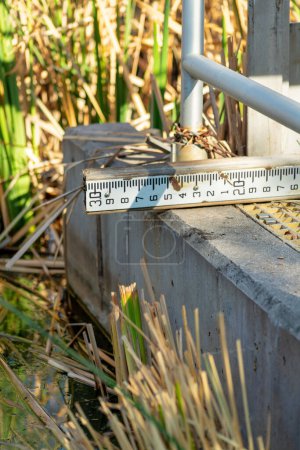 Téléchargez les photos : Measuring ruler to determine how much water or rain there is in the local pond or lake in industrial area. Used by scientists and government officials to calibrate the flow rate of the river. - en image libre de droit