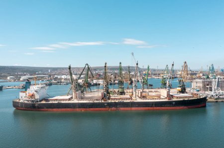 Black Sea Grain Initiative 2023 grain Deal. Port cranes loading of grain on a bulk carrier at sunny day. Panoramic shot made by drone
