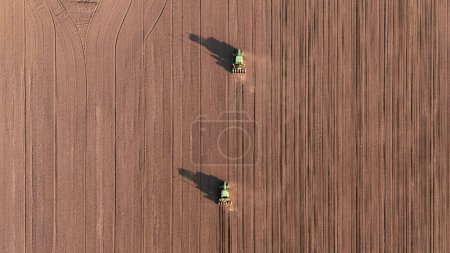 Seeds to sow. Few Tractors with seed drills sowing the crop, top down view from drone