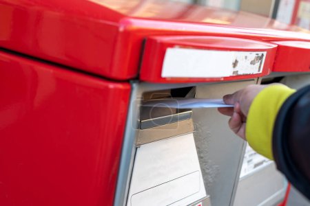 Foto de A hand dropping off an envelope into a red post mail box - Imagen libre de derechos