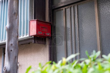 Téléchargez les photos : Une vieille boîte aux lettres rouge à l'entrée d'une maison japonaise. - en image libre de droit