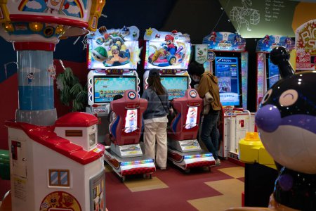 Téléchargez les photos : Une famille joue à un jeu de course Mario dans un centre de jeux d'arcade au Japon. - en image libre de droit