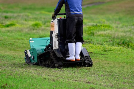 A person riding and operating a flail mower to mow the grass in the yard.
