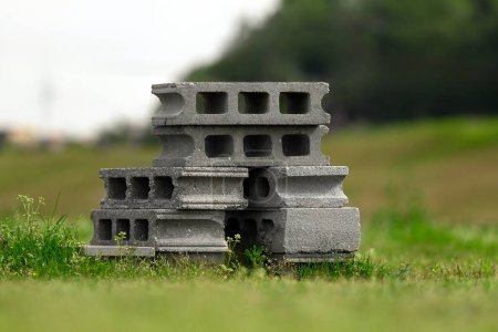 A pile of concrete hollow blocks stacked on top of each other in the grass. 