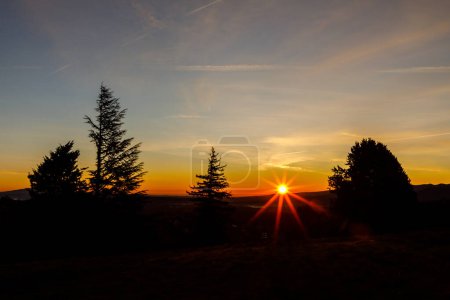 Foto de Puesta de sol en las montañas con lago de agua en el valle y rayos de sol en el cielo azul. Navacerrada Madrid. España. - Imagen libre de derechos