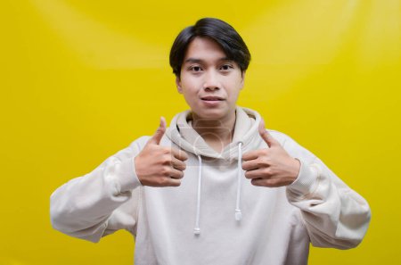 Foto de Para conceptos de publicidad y colocación de productos, un joven asiático feliz y sonriente abre sus palmas y apunta a copiar espacio - Imagen libre de derechos