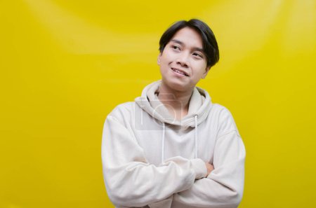 Téléchargez les photos : Un homme asiatique réfléchi et confus pensant et se demandant s'il faut choisir quelque chose d'isolé sur un fond jaune - en image libre de droit