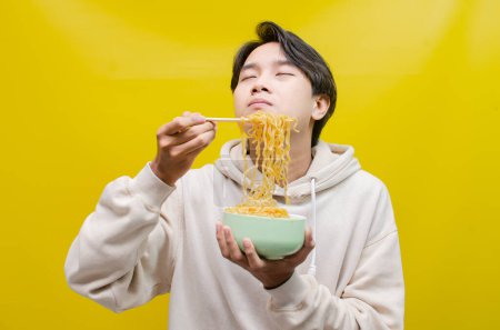 Photo for Asian man smelling and enjoying with pleasure delicious noodles. a man gives delicious expressions while eating noodles. - Royalty Free Image