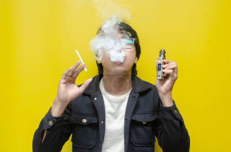 Photo for Young Asian man choosing between vape and cigarette - Royalty Free Image