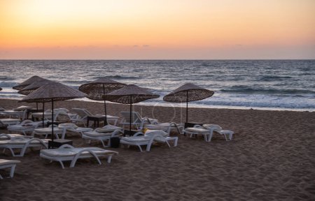 Empty sun loungers on the beach in evening time on sunset