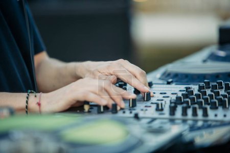 Close up view of a djs hands playing the mixer while performing in a music festival. High quality photo