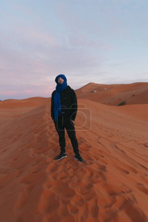 Photo for General view of a man with a Berber scarf spotting the horizon from the top of a dune in the Sahara desert. High quality photo - Royalty Free Image