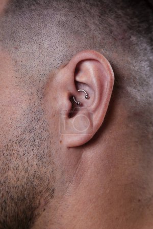 Outer ear black tragus piercing on adult white man. High quality photo