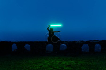 Vista general de un caballero jedi sosteniendo un sable de luz a la hora borrosa. Foto de alta calidad