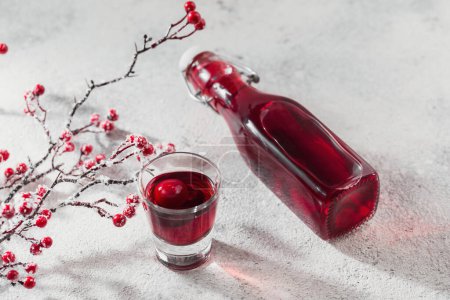 Téléchargez les photos : Vodka infusée maison, teinture ou liqueur de cerise rouge sur fond blanc. Concept de boissons alcoolisées aux baies. - en image libre de droit