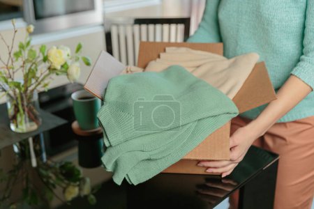 Second hand clothes in cardboard box. Woman packing box with used wardrobe for resale. Circular fashion, fast fashion, Sustainable ethical consumption and shopping, thrifting shop concept.